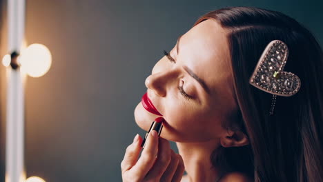 woman applying lipstick in front of a mirror