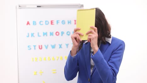 female teacher with whiteboard and notebook in classroom
