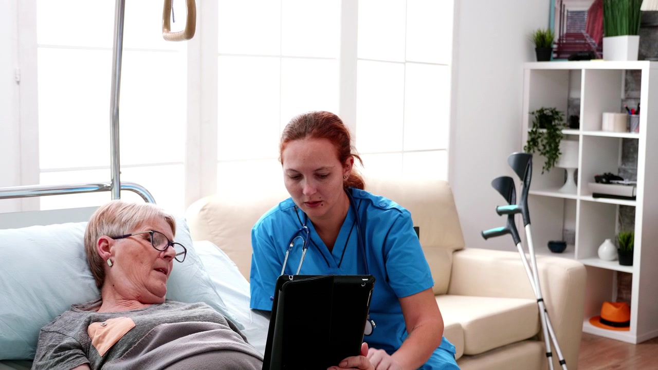 Nurse Showing Medical Information on Tablet to Senior Patient in Bed