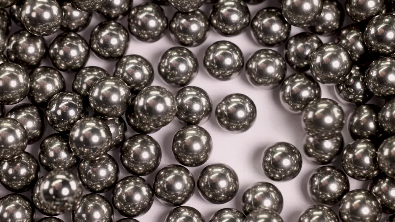 Close-up video of ball bearings falling and colliding, showcasing dynamic movement and metallic reflections under bright lighting