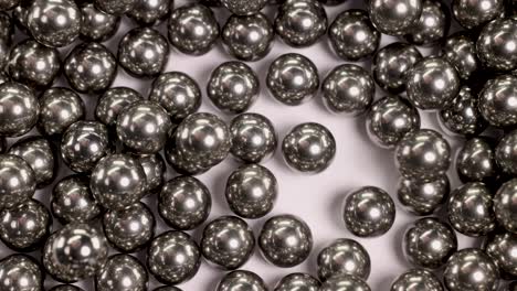 close-up video of ball bearings falling and colliding, showcasing dynamic movement and metallic reflections under bright lighting