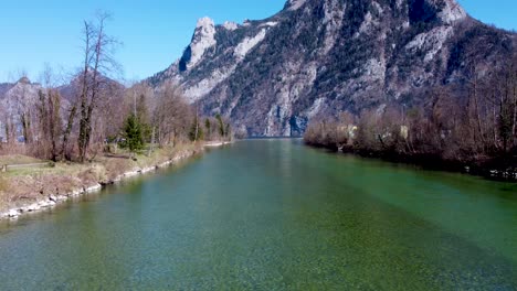 Calm-river-Traun-flowing-through-Ebensee-with-Traunstein-mountain-backdrop,-sunny-day