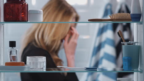 view through bathroom cabinet of anxious woman waiting for home pregnancy test result