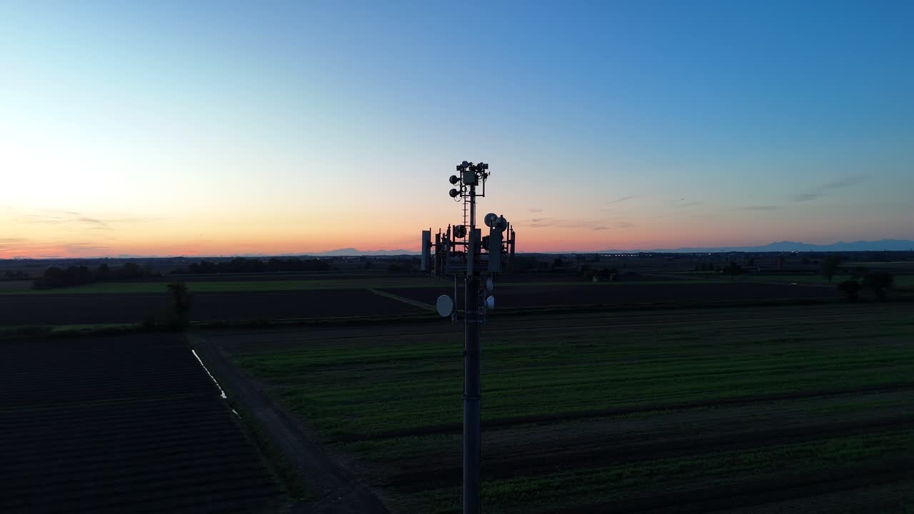 Aerial view of a modern 5G cellular tower with multiple antennas installed in a rural Italian landscape during twilight