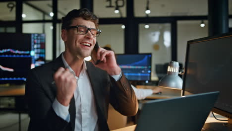 cheerful manager enjoying call news in evening workplace. stock happy man broker