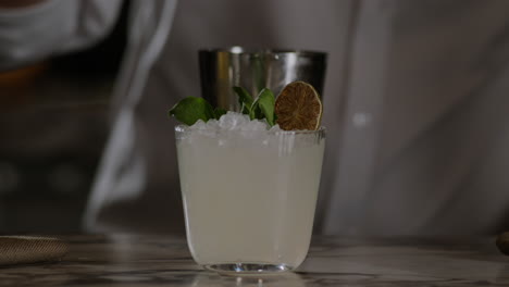 bartender garnishes a margarita with a candied lime