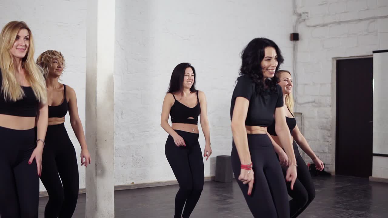 Group of attractive sexy women learning hand moves of bachata dance. Dancing class.