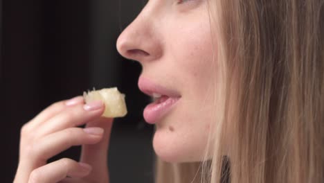 woman eating juicy slice of pomelo at kitchen, close up portrait