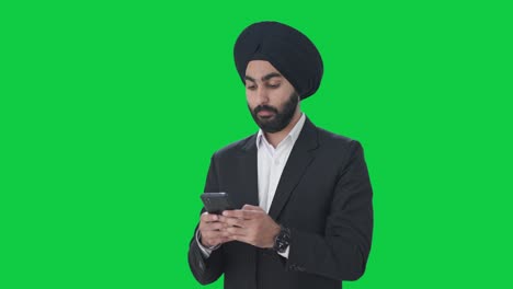 Un-Hombre-De-Negocios-Indio-Sikh-Serio-Enviando-Mensajes-De-Texto-A-Alguien-Con-Pantalla-Verde