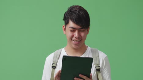 close up of asian man student using tablet on green screen studio