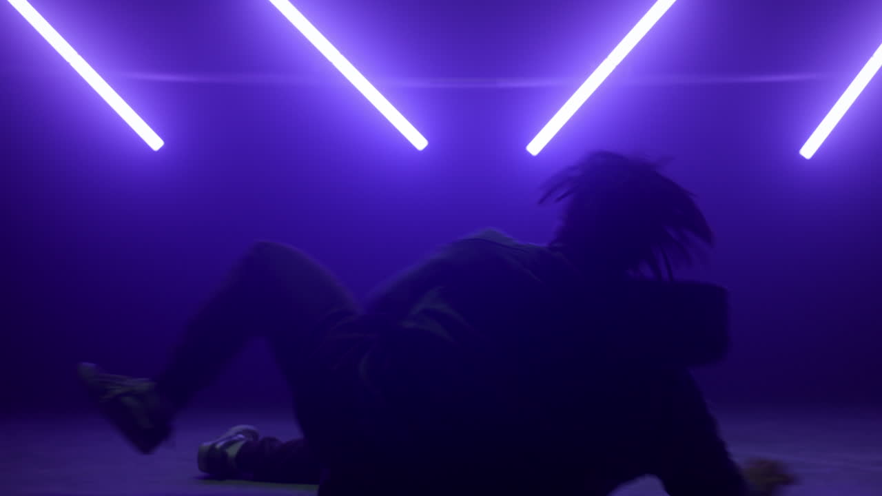 b-boy genial mostrando movimientos de hip hop en el club. bailarín de silueta actuando.