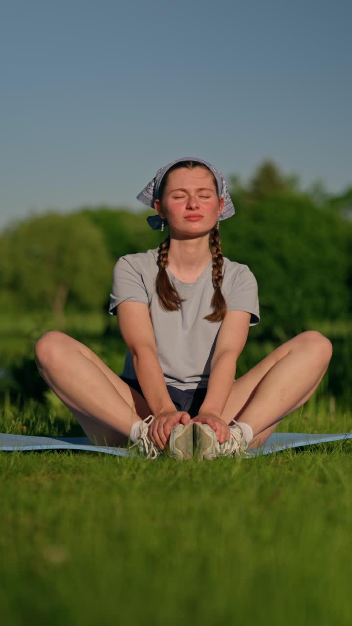 A Gen Z woman sits in a peaceful park, becomes pensive, settles into a meditation pose, and reaches calm well-being. Smooth vertical 4K left-dolly shot capturing a strong emotional wellness moment