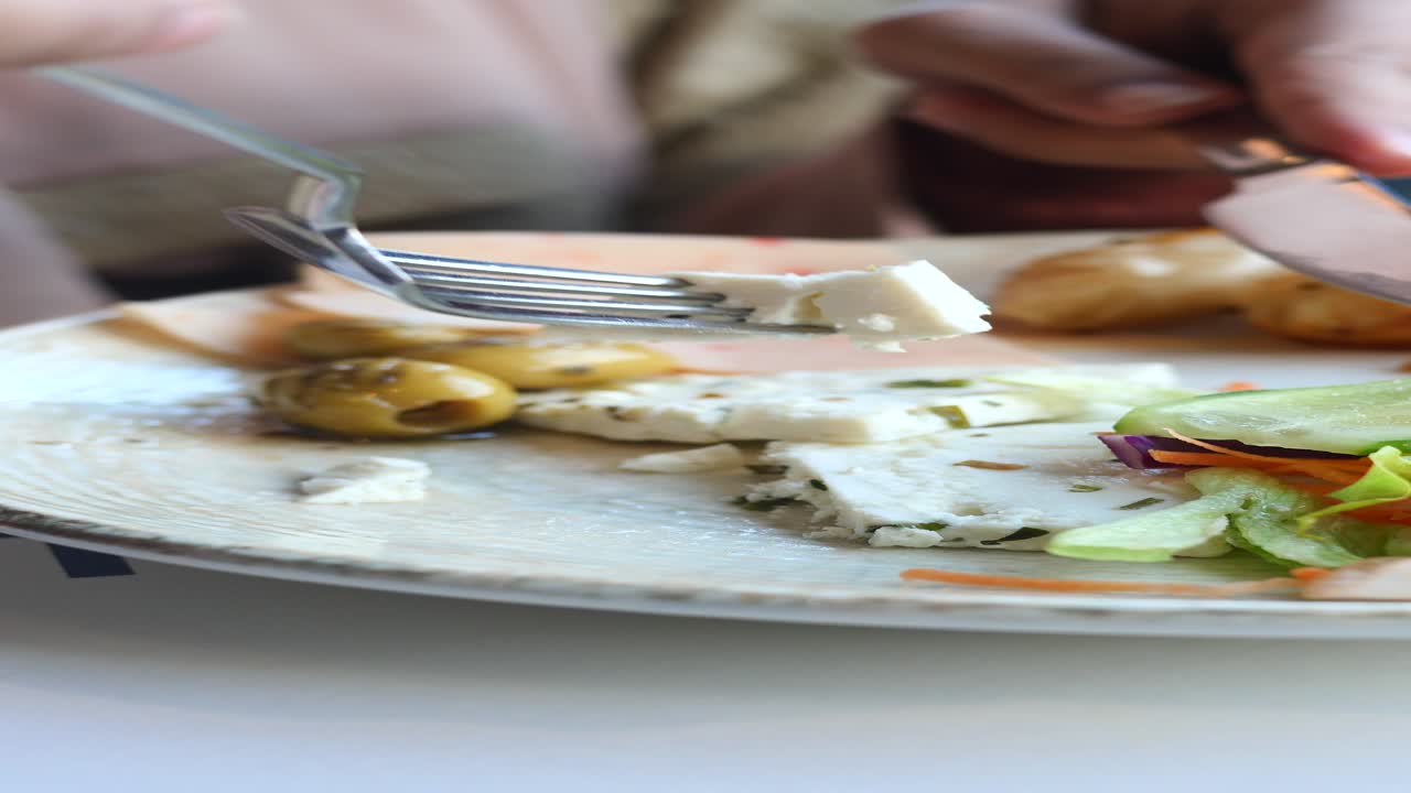 mujer comiendo una comida con queso, aceitunas y ensalada