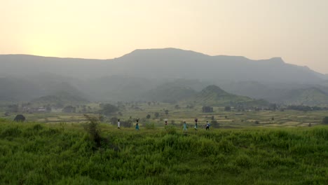 people walking in grassy countryside path of karjat mumbai in india - aerial shot