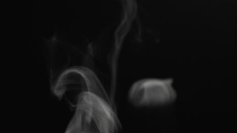 close up steam particles swirling and rising on a black background in slow motion