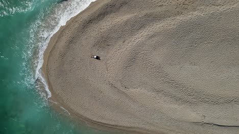 male tourist lying on famous beach zlatni rat in croatia. drone is going up, zoom out shot
