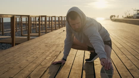 man stretching on a wooden boardwalk at sunset