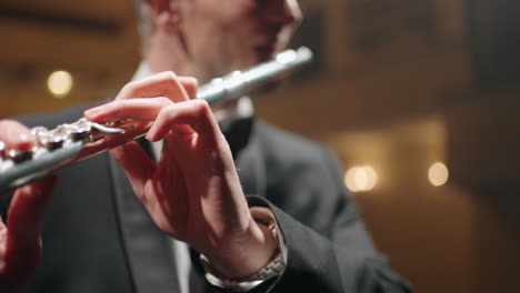 flautista profesional está tocando la flauta en el salón filarmónico ensayo o concierto de orquesta sinfónica primer plano