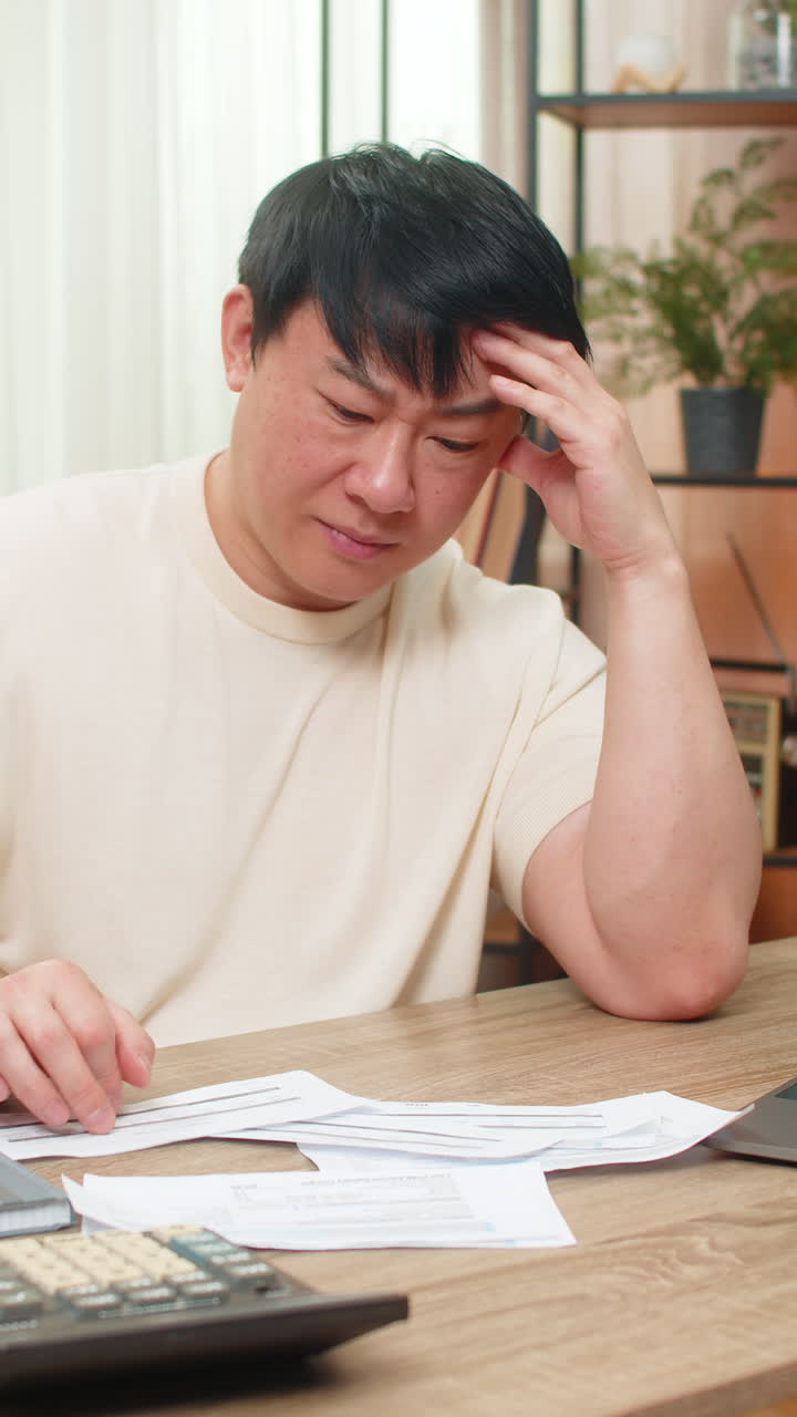 Asian man throwing bills onto table after shocking amount eyebrows raised very frustrated reaction