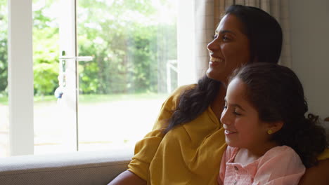 Madre-E-Hija-En-Casa-Sentadas-En-El-Sofá-Viendo-Televisión-Juntas