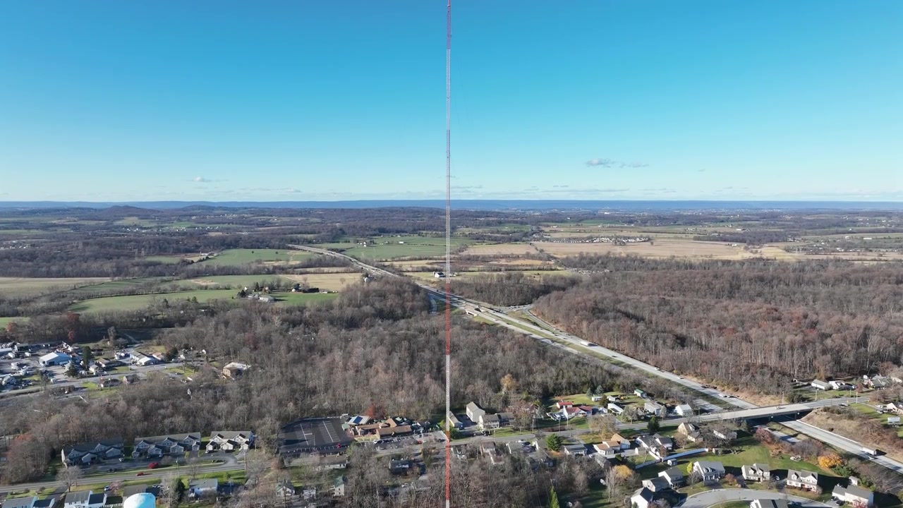 Vista aerea di un quartiere periferico con autostrada e alberi della foresta senza foglie. Giornata di sole con cielo blu negli USA. Abitazioni e case vicino all'interstatale. Torre di trasmissione che fornisce segnale.