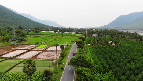 Drone-shot-of-a-truck-driving-through-Tamil-Nadu-surrounded-with-beautiful-nature,-near-Vellore,-India