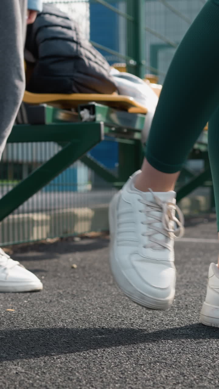 vista lateral de un atleta en zapatillas deportivas y corredores entrando en una cancha deportiva, pasando por un banco con una chaqueta puesta sobre él, destacando el comienzo de una sesión de entrenamiento