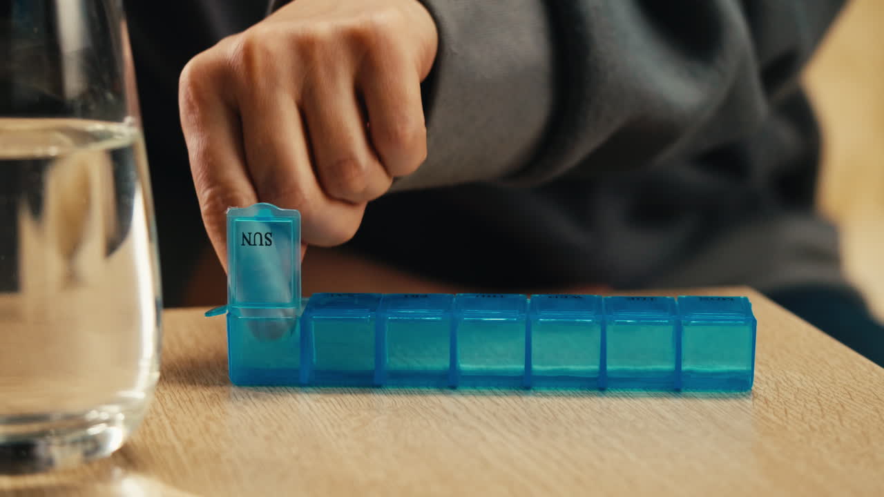 persona que toma medicamentos de un organizador de pastillas
