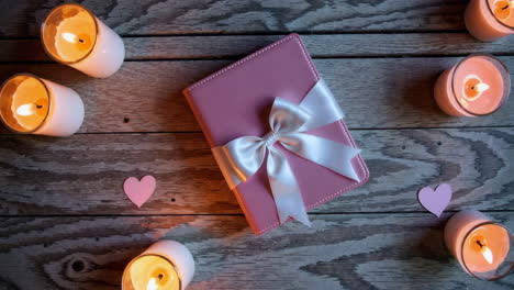 Pink Gift Box with Candles and Hearts on Wooden Background