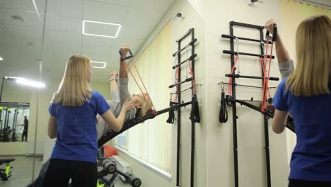 various scenes of people working out in a gym including a woman doing exercises with a resistance various gym scenes a woman using a resistance band helping a man workout nurse assisting a woman on a machine focus on physical fitness and teamwork in an engineering of balance and fun event