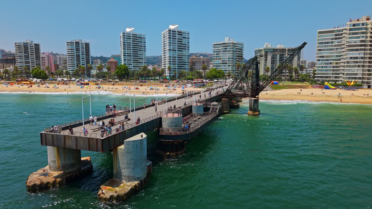 Inquadratura aerea panoramica che mostra il molo Vergara con turisti che passeggiano e si godono una giornata di sole a Viña del Mar, Cile.