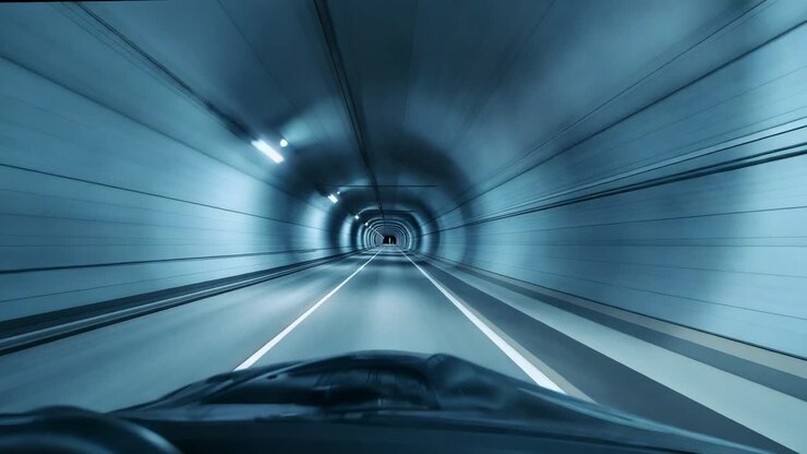 Auto che entra in un tunnel, mantenendo la rotta verso l'uscita con vista sul cruscotto e segnaletica orizzontale
