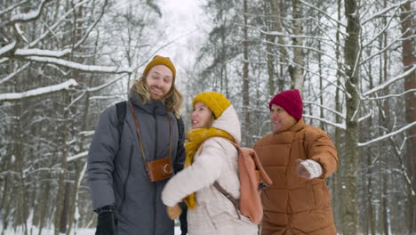 front view of three friends in winter clothes walking in a winter forest