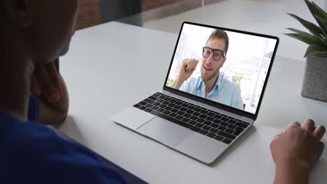 African-american-woman-talking-on-video-call-with-male-colleague-on-laptop-at-office