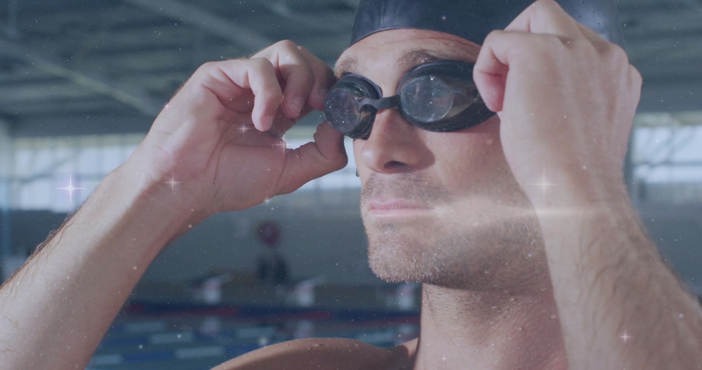 Swimmer fitting goggles in swimming pool, sending sparkles highlighting tight seal