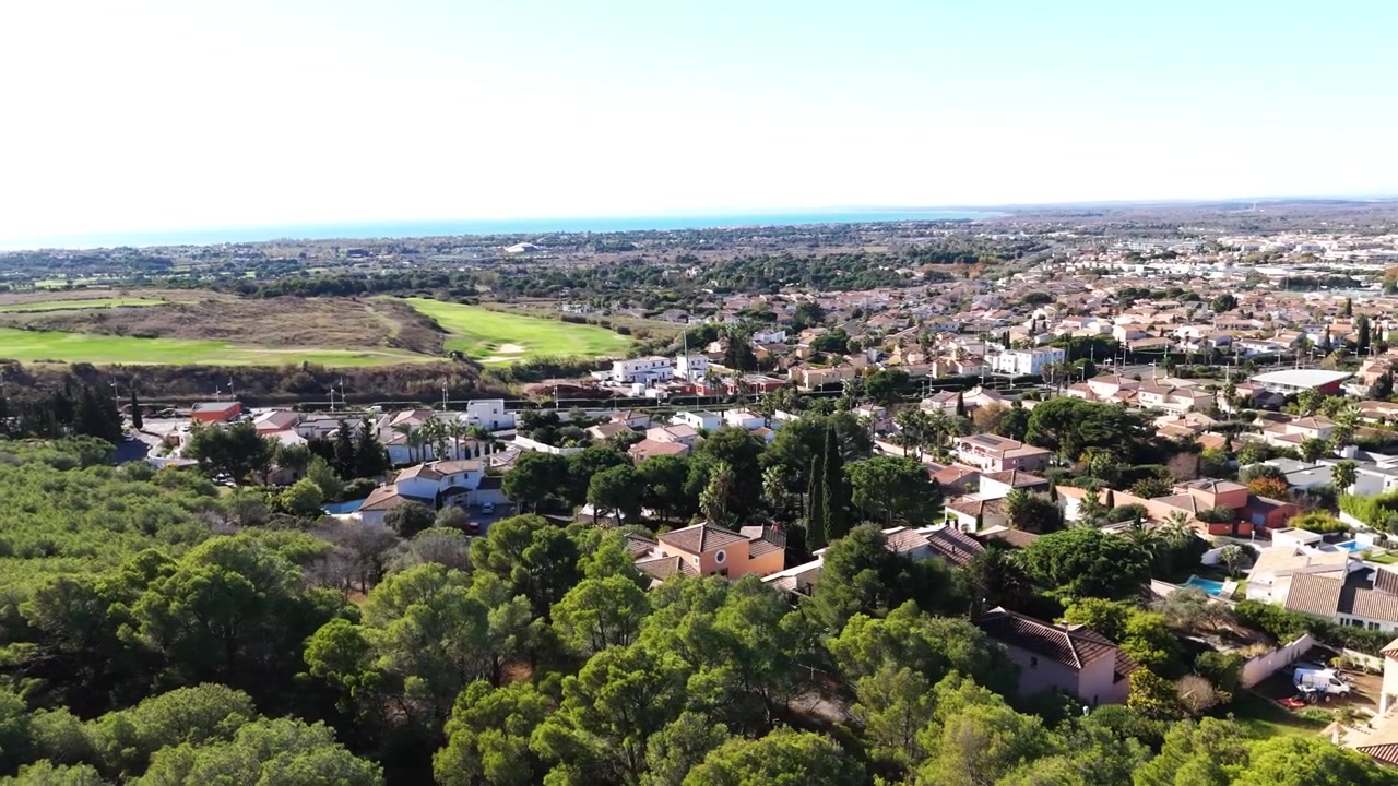 Ripresa aerea con drone di Agde, città della Francia meridionale. Paesaggio mediterraneo con case residenziali, pini e vista costiera in estate.
