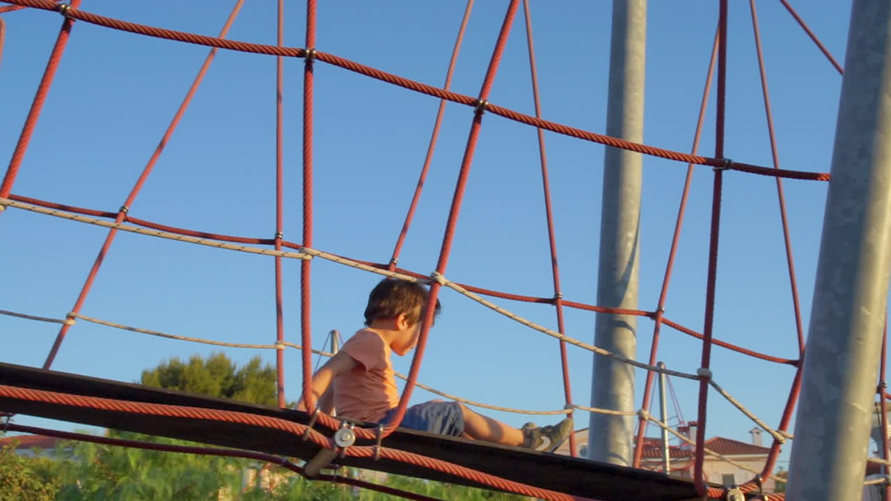 un niño camina sobre un puente de cuerda en un parque