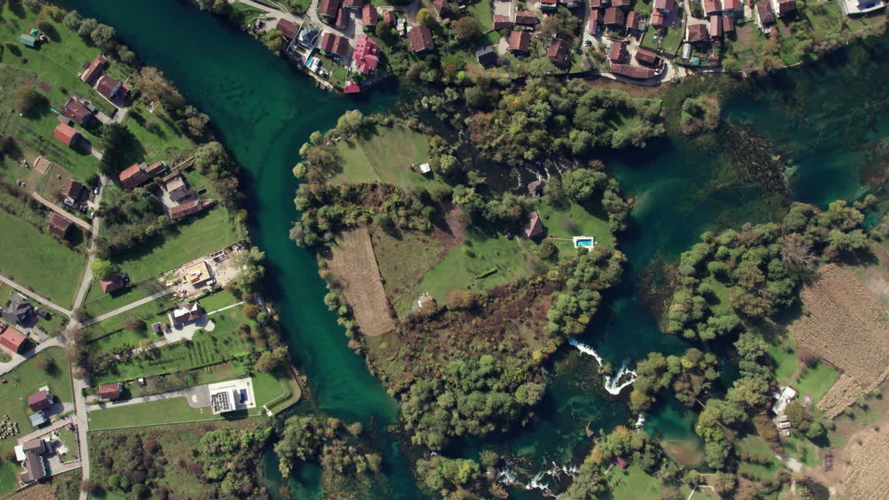 Aerial top view of the Una River forming a natural heart shape surrounded by green forest and rural landscape near Bihac, Bosnia and Herzegovina. Clear turquoise water seen from above