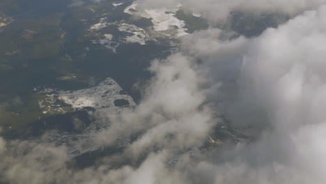 vista desde un helicóptero volando sobre las montañas rocosas con nubes finas sobre colinas nevadas y boscosas
