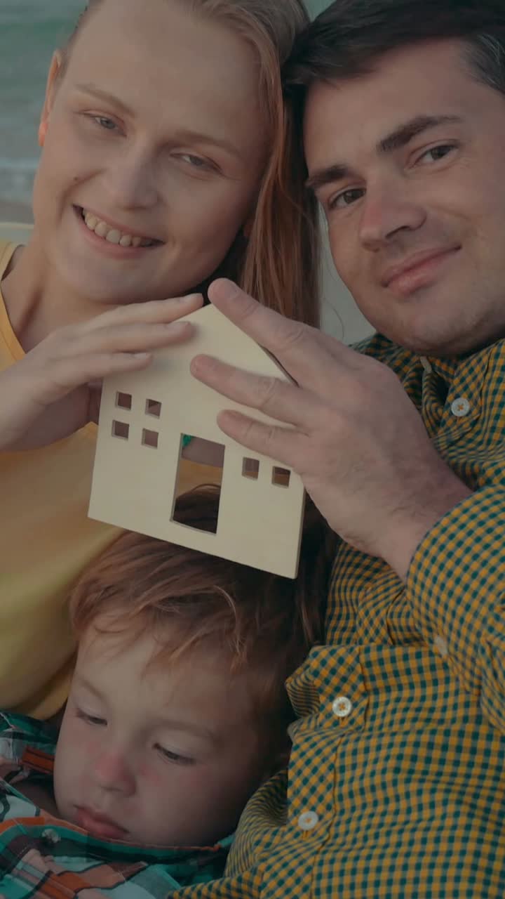 Happy Family Holding a Wooden House