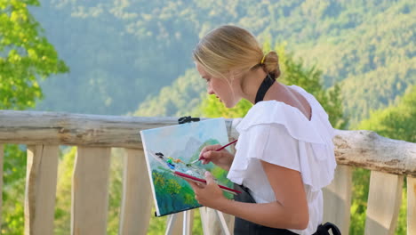 woman painting a mountain landscape outdoors