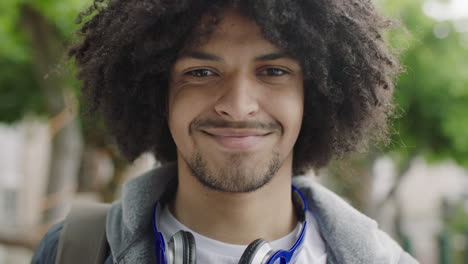 close up portrait of young mixed race student man smiling confident looking at camera enjoying independent lifestyle in urban city trendy afro hairstyle