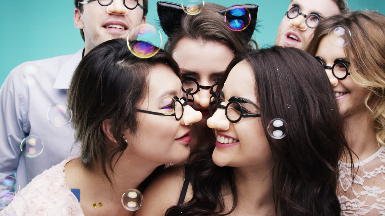 grupo multi-racial de personas que usan narices falsas cámara lenta cabina de fotos de la fiesta