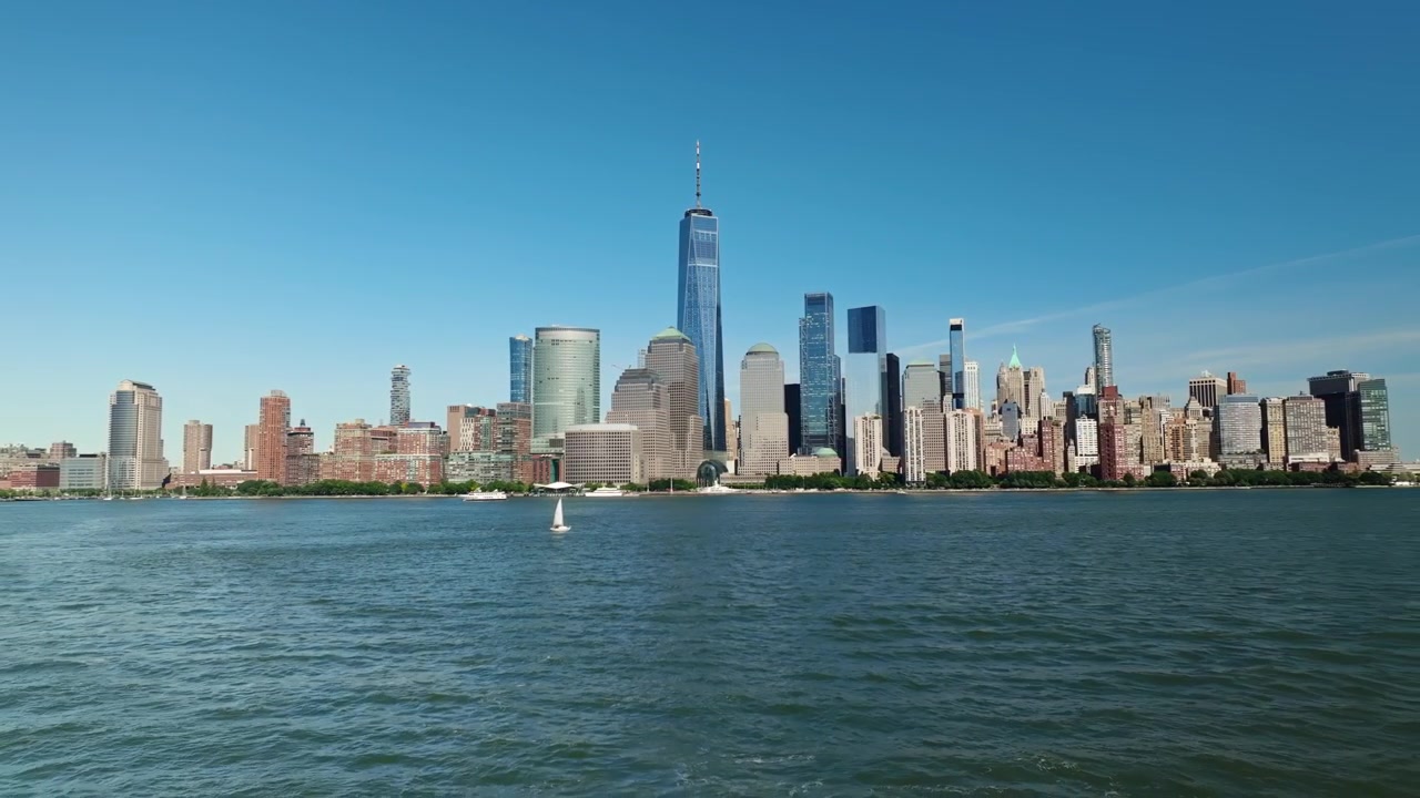 Edifícios memoriais icônicos da cidade de Nova York contra o céu azul com vista para o Rio Hudson, em afastamento aéreo.