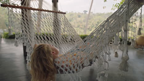 Mujer-Feliz-En-Una-Hamaca-Balanceándose-Pacíficamente-En-Un-Perezoso-Día-De-Verano-Disfrutando-Del-Estilo-De-Vida-De-Vacaciones-En-El-Complejo-Vacacional