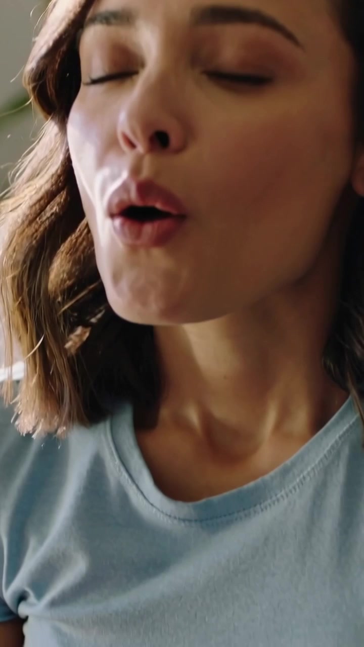 Video verticale: Donna sorridente con una maglietta blu che stringe le labbra ed espira a casa, con una pianta in vaso.
