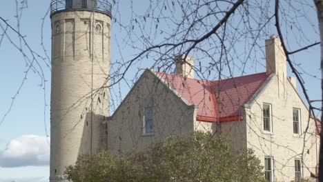 Alter-Mackinac-Point-Leuchtturm-In-Mackinaw-City,-Michigan,-Mit-Auf-Einer-Dolly-Gedrehtem-Kinovideo-Mit-Bäumen-Im-Vordergrund,-Die-Sich-Von-Rechts-Nach-Links-Bewegen