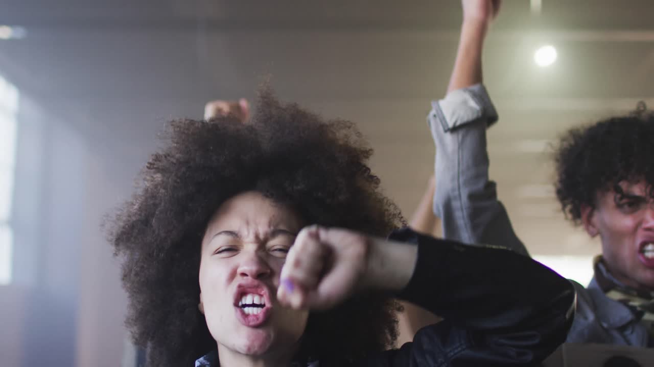 grupo diverso de personas con máscaras faciales sosteniendo carteles de protesta gritando levantando puños