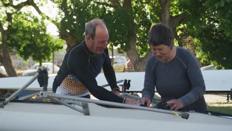 senior caucasian man and woman preparing rowing boat for the water