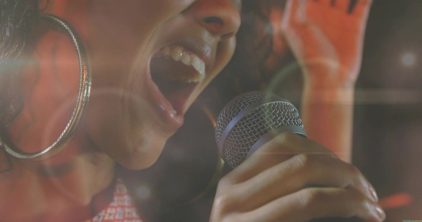 Woman singer holding mic and starting note, belting then easing music, lens flares overlaying face